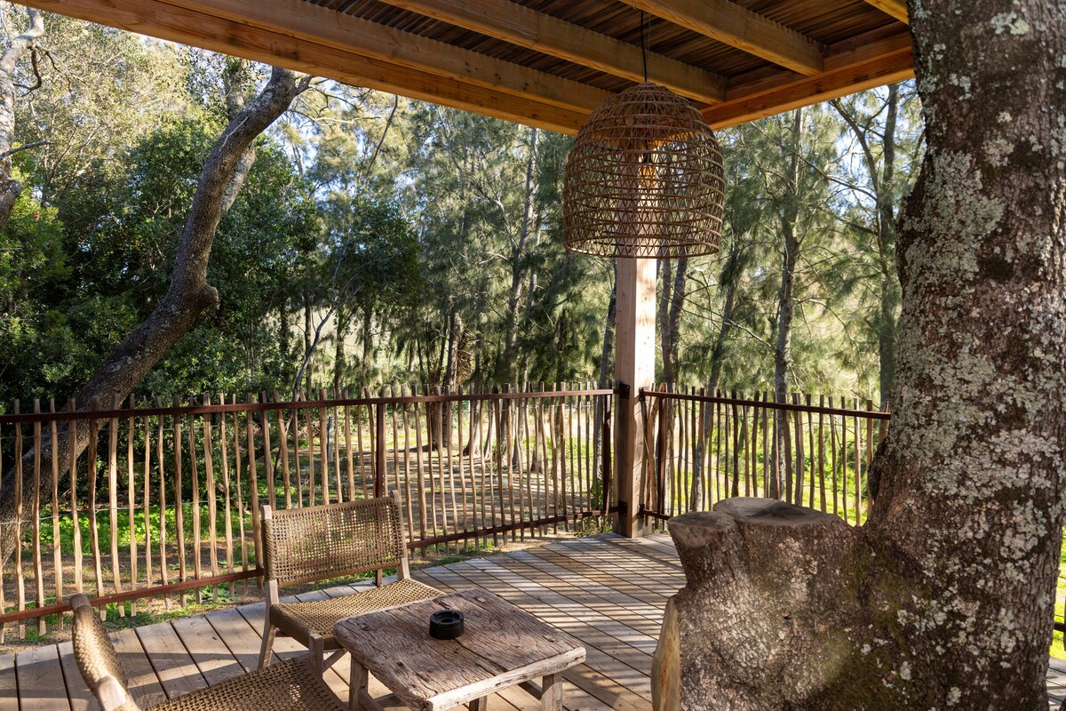 A wooden deck with wicker furniture, a hanging light fixture, and a metal fence.