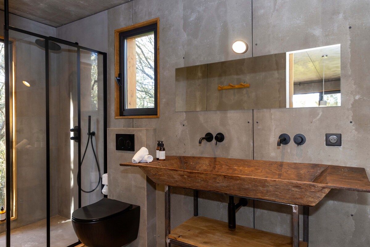 A modern bathroom with a wooden vanity, a large mirror, and a glass shower enclosure.