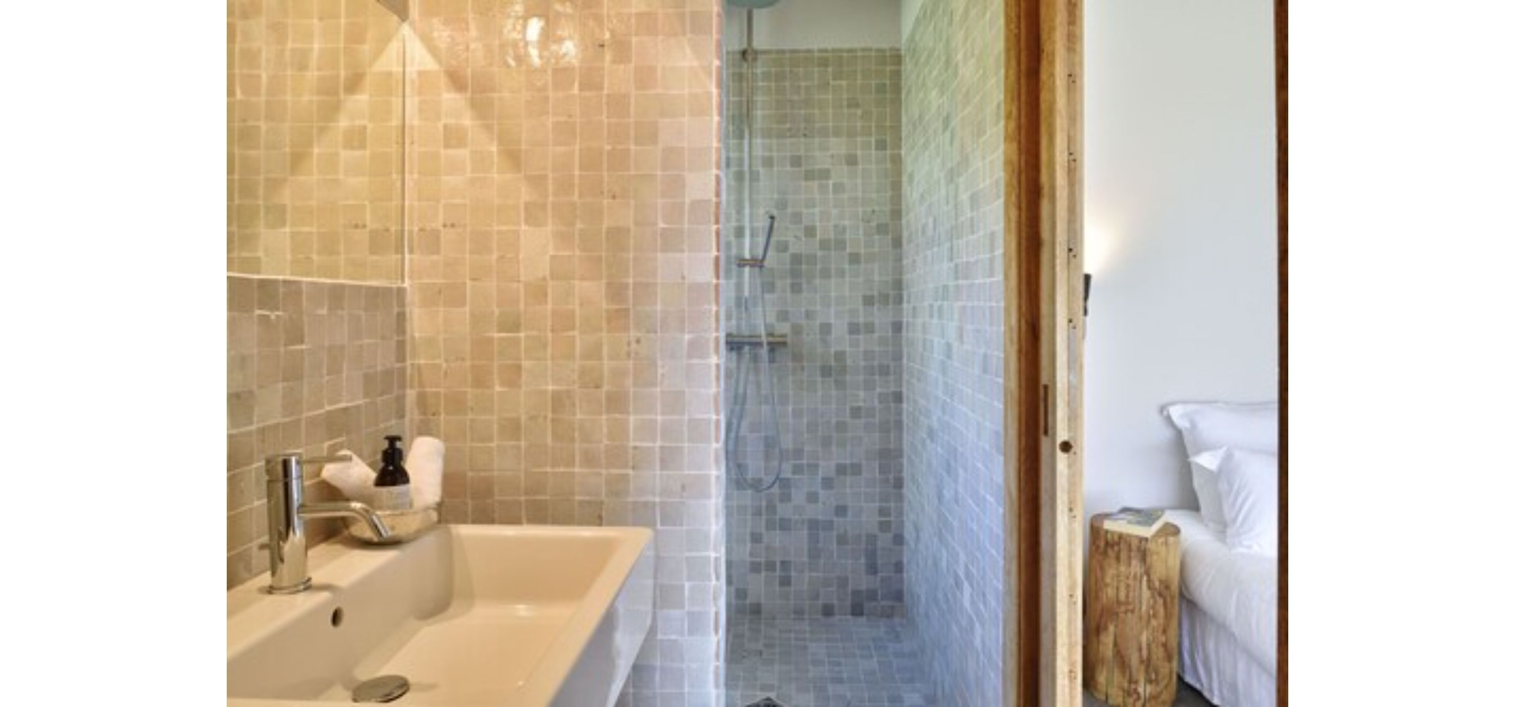 A bathroom with a bathtub, a shower area, and a wooden stool.