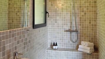 A bathroom with a sink, mirror, shower, and tiled walls.