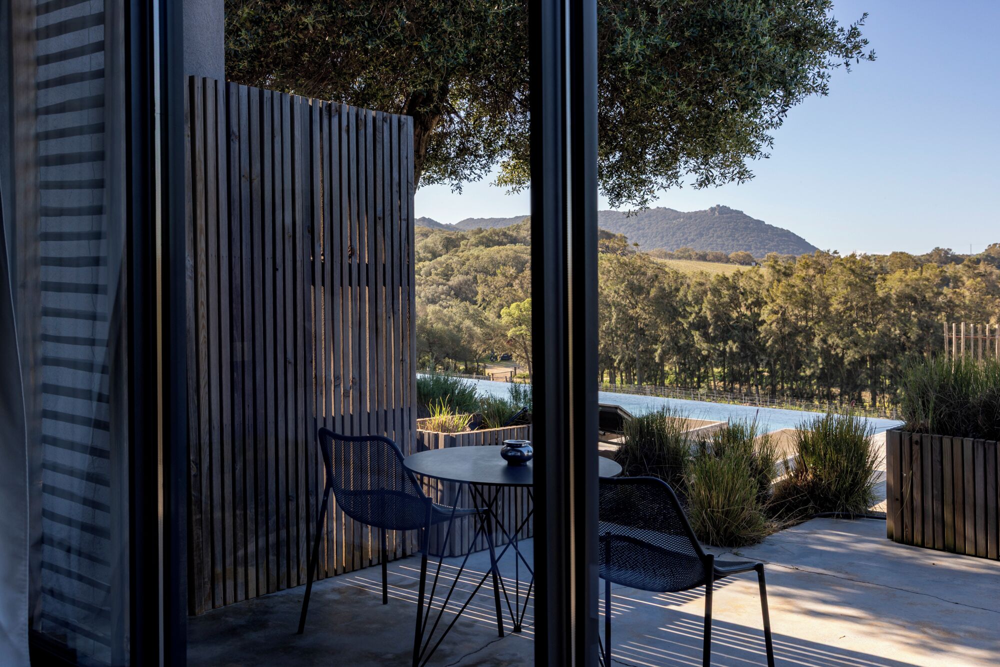 Un espacio al aire libre con mesa y sillas, una cerca de madera y vistas a un lago y montañas.