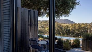 Un espacio al aire libre con mesa y sillas, una cerca de madera y vistas a un lago y montañas.