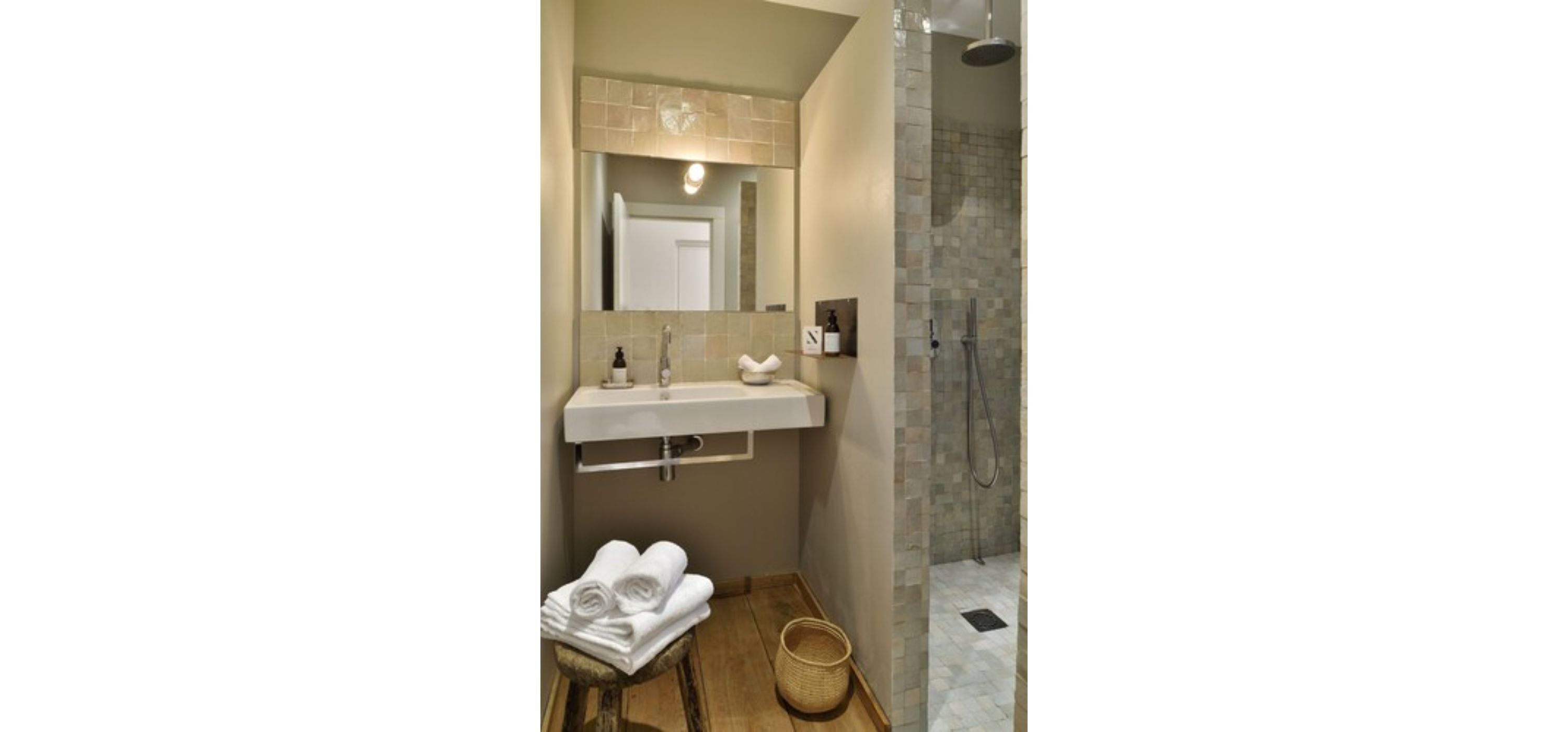 Une salle de bain avec un lavabo, un miroir et une douche.