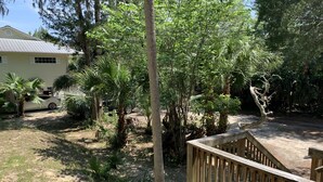 Una terraza de madera con vista a una casa y follaje circundante.