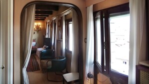 A narrow corridor with a curved wall, a bed, a chair, and a small table. - Ca' San Lorenzo spectacular view (Venezia)