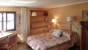 A hotel room with a bed, a desk, a chair, a bookshelf, and a window with curtains. - Ca' San Lorenzo spectacular view (Venezia)