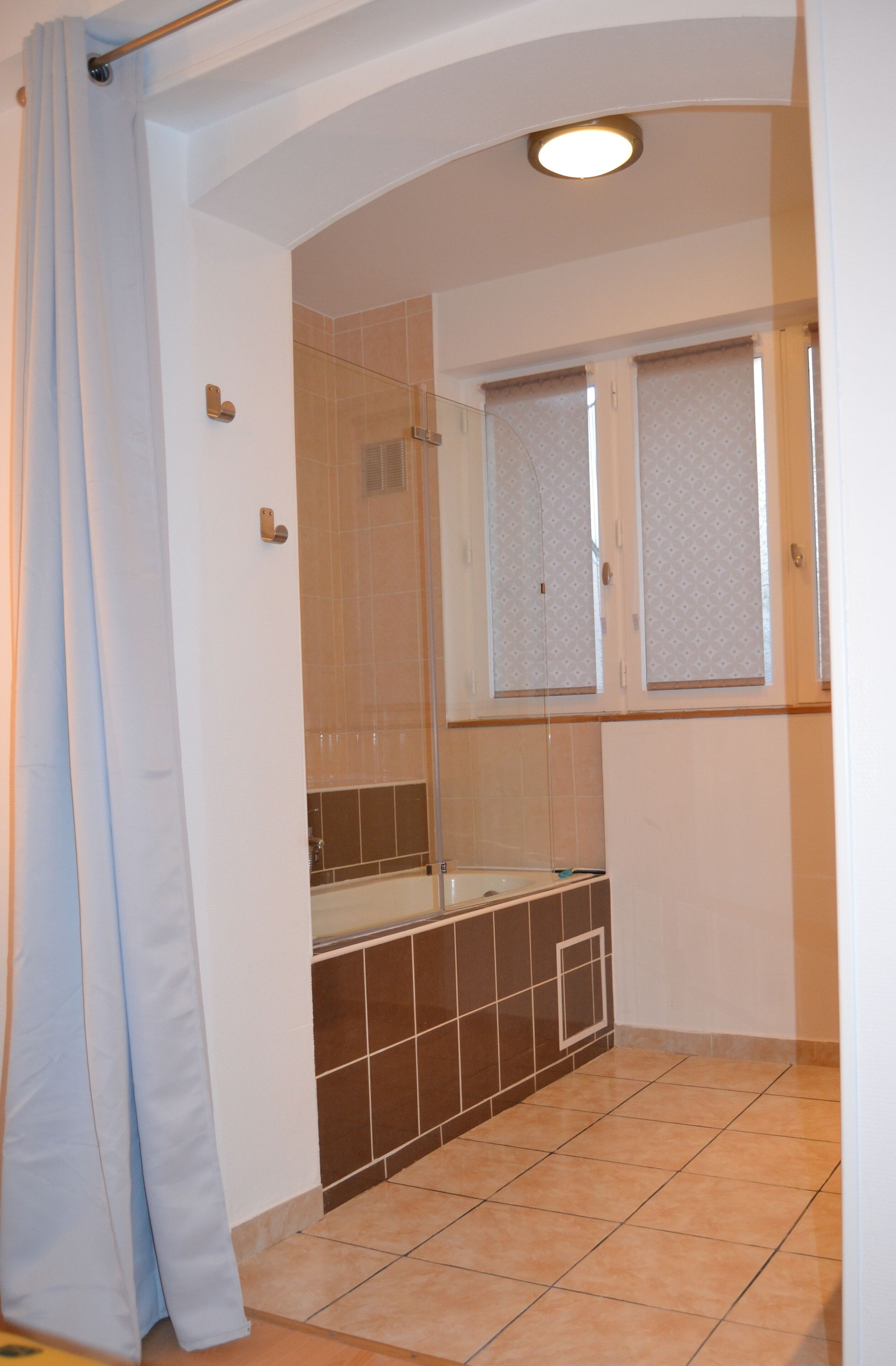 A bathroom with a bathtub, a shower, and a window with frosted glass.
