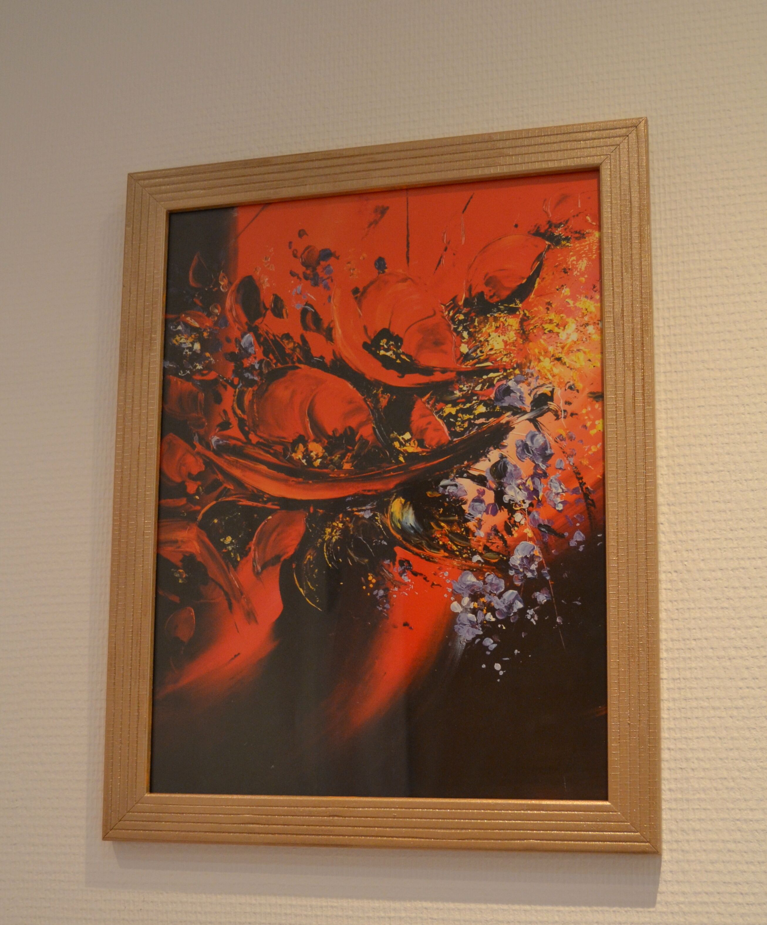 Ein abstraktes Gemälde in einem Rahmen an einer strukturierten Wand.