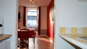 Une cuisine avec une table et des chaises en bois, un four à micro-ondes et un rideau rouge.