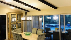 A dining area with a table and chairs, a ceiling fan, and a view of an outdoor patio. - Hot Tub, Heated Pool and near Cape Coral, Punta Gorda Fort Myers & Naples  (North Fort Myers)