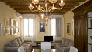 Un salon spacieux doté d’un grand plafond en bois, d’une table basse en verre et de deux canapés placés face à un téléviseur à écran plat.