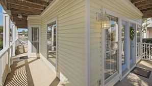 Une véranda couverte avec un plafond en bois et un revêtement extérieur blanc.
