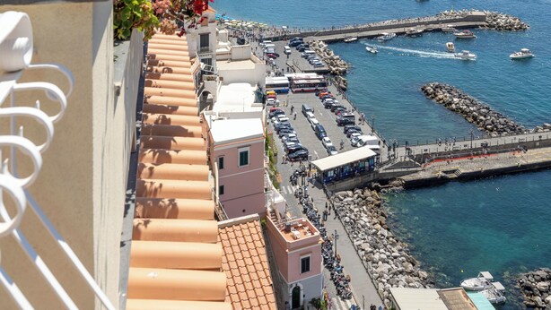 A coastal view with boats, a pier, and a building with a balcony. - Apartments Amalfi Design Sea View (Amalfi)