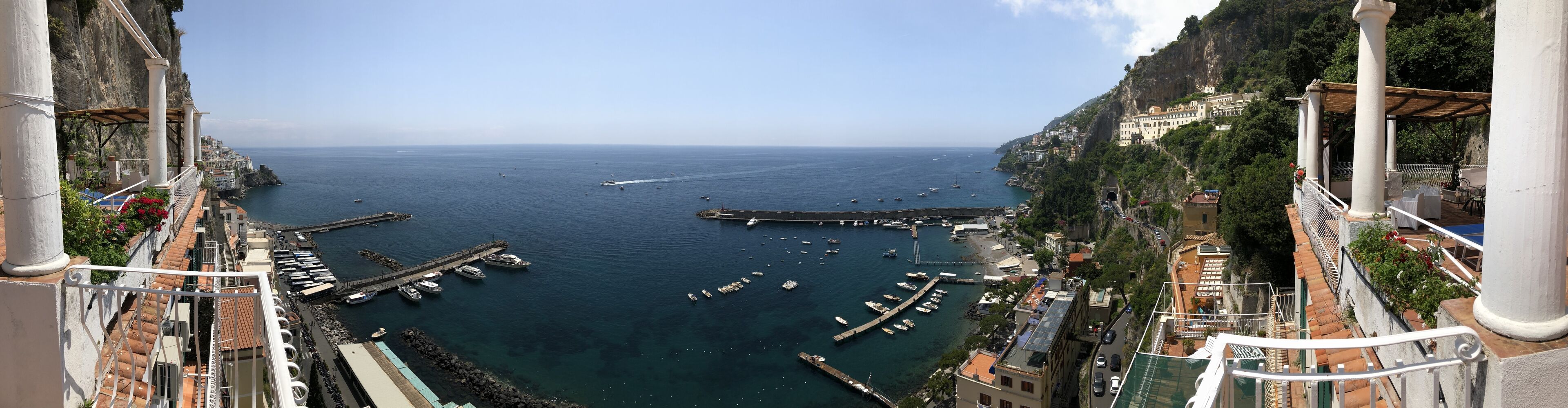 Uma vila costeira com um porto de iates, edifícios ao longo do penhasco e vista clara para o mar.