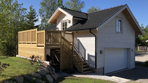 Een huis met twee verdiepingen, een overdekte veranda, een garage en een trap naar de bovenverdieping.