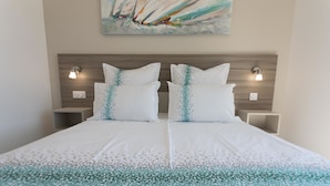 A double bed with a white and teal patterned bedspread, two white pillows with teal accents, wooden headboard, and two bedside tables with wall-mounted lamps. - Luxury Villa With Private Pool in Cesseras (Cesseras)