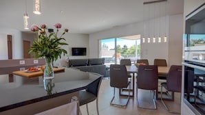 A modern kitchen with a dining area, large windows, and a flat-screen TV. - Luxury Villa With Private Pool in Cesseras (Cesseras)