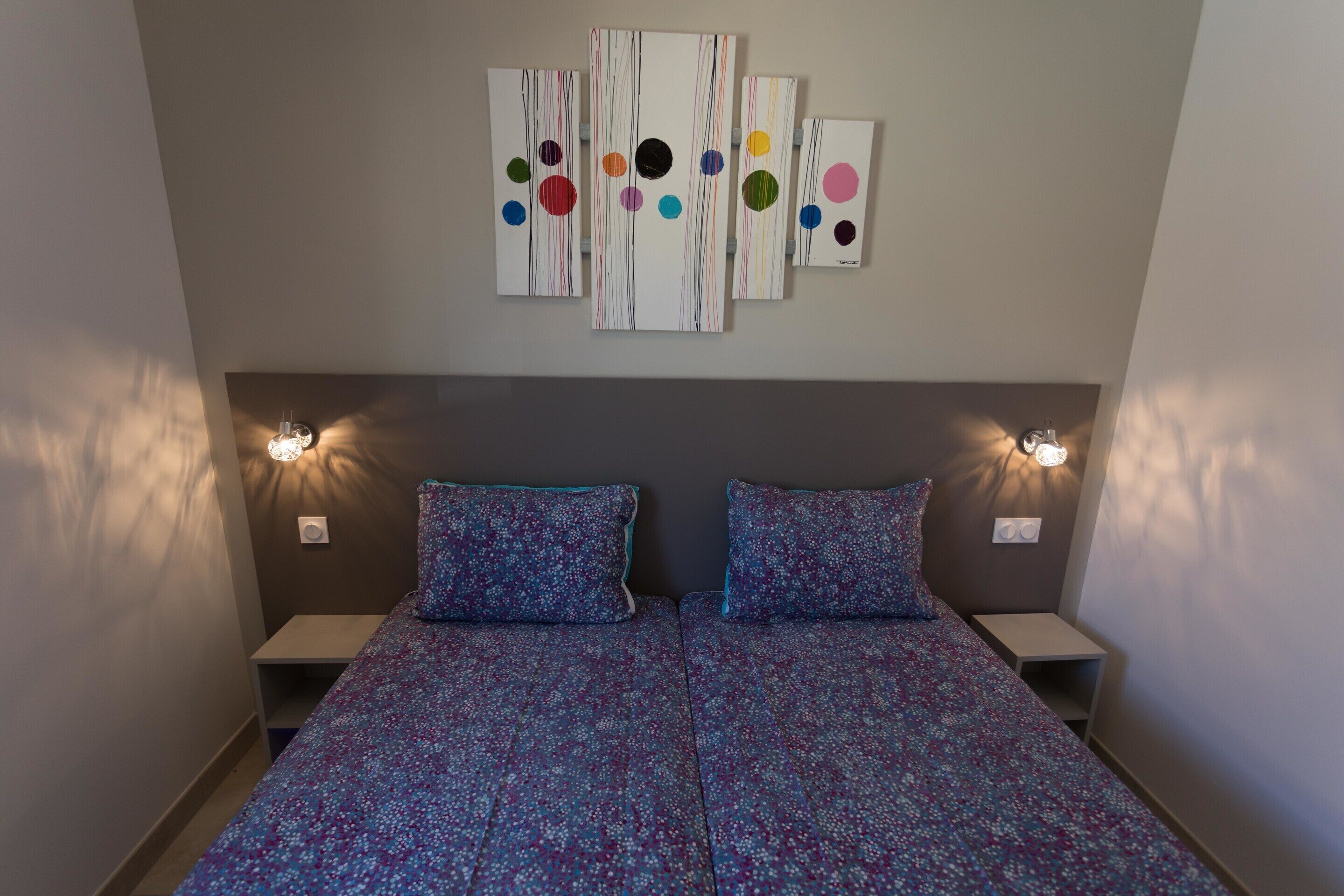 Een slaapkamer met een bed, twee nachtkastjes en wandlampen.