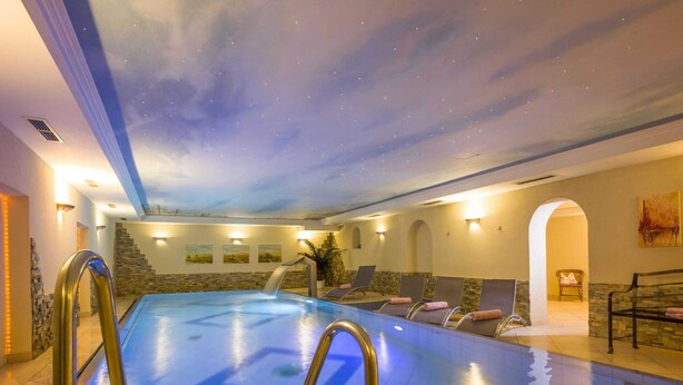 A swimming pool with a starry ceiling, lounge chairs, and a stone wall. - Apartment in Stumm Near Zillertal Ski Area (Stumm)