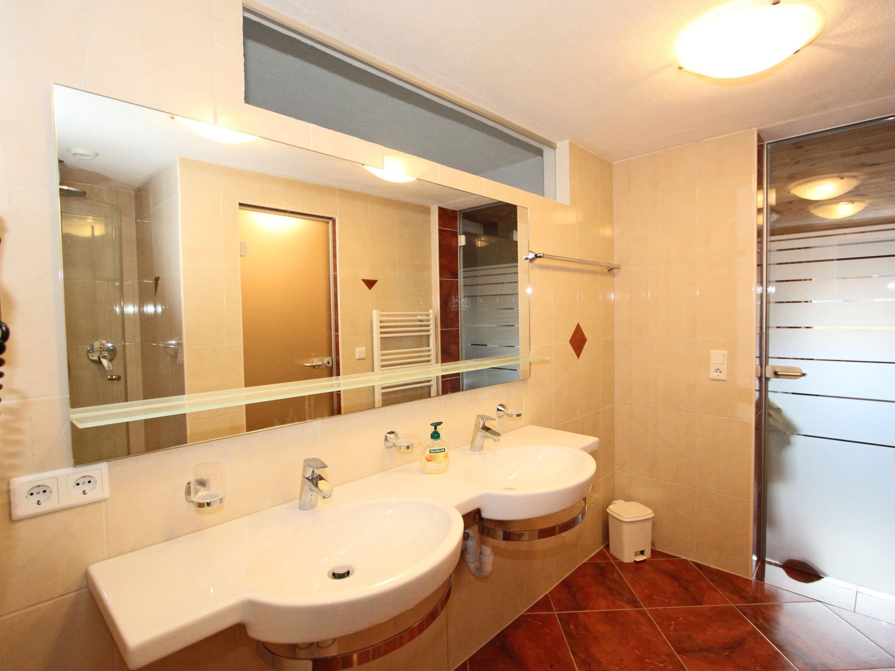 Ein Badezimmer mit zwei Waschbecken, einem Spiegel und einer Dusche.