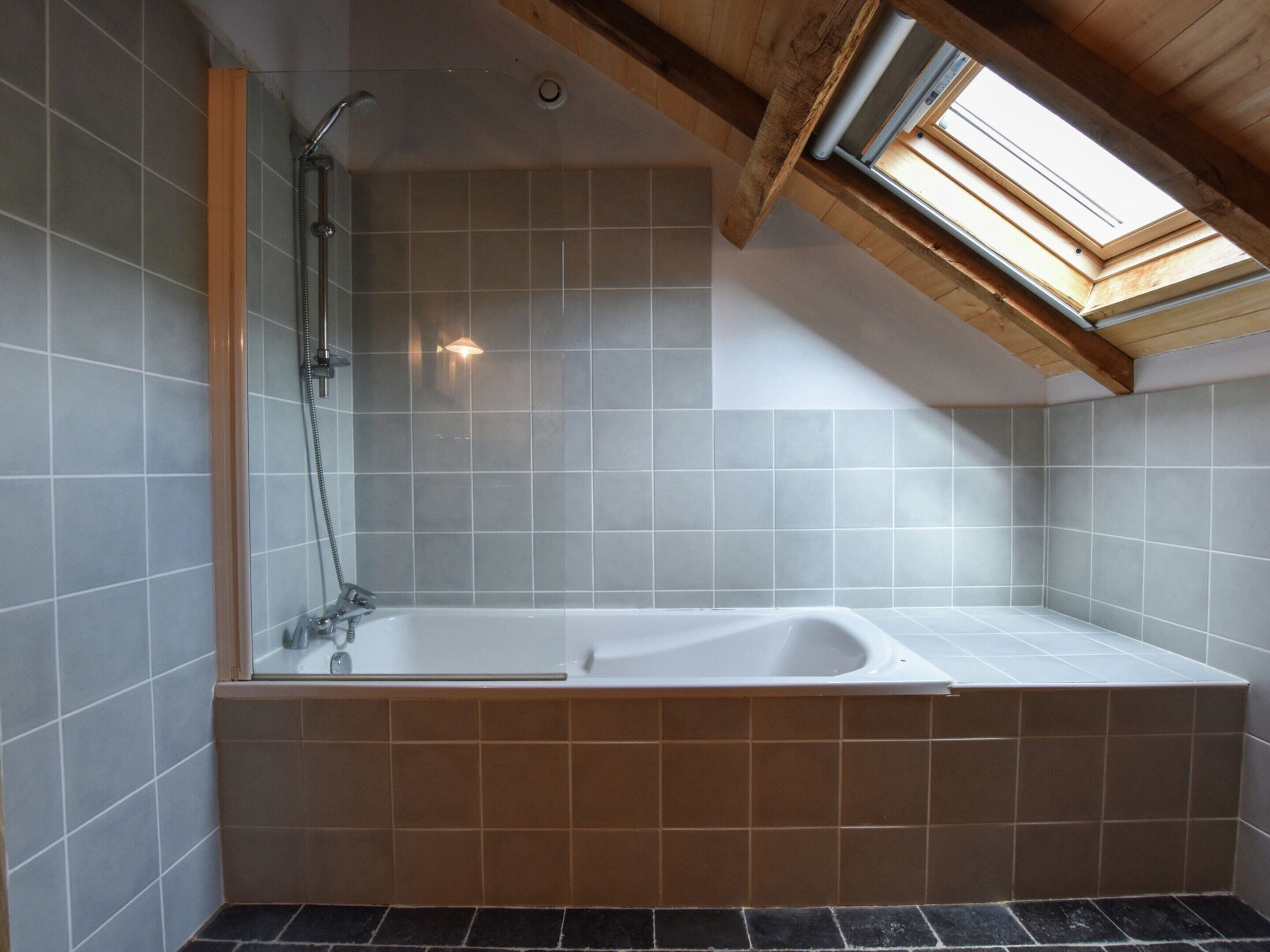 Une salle de bain moderne avec un puits de lumière, une douche et une baignoire.