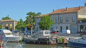 A marina with boats docked, a building with a sign, and a clear blue sky. - Courry Gem: Pool & Charm (Courry)