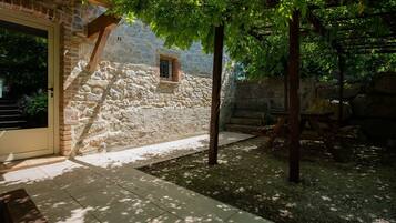 A stone building with a door, a small window, and a wooden pergola.