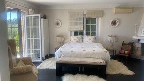 A bedroom with a bed, a chair, a fireplace, and a view through a window. - Villa in Grasse With Private Pool (Grasse)