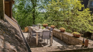 An outdoor dining area with stone tables and chairs, surrounded by potted plants and a stone wall. - Pool Escape in Saint-laurent (Saint-Laurent-la-Vallee)