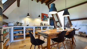 A spacious kitchen with wooden beams, a dining table with chairs, pendant lights, and a kitchen island with storage. - Pool Escape in Saint-laurent (Saint-Laurent-la-Vallee)