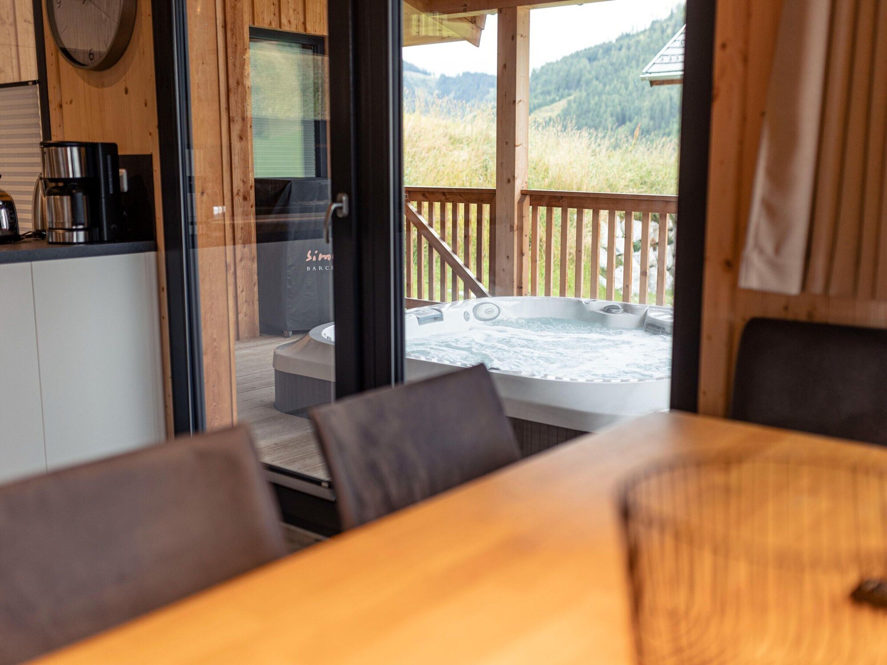 A wooden deck with a hot tub and a view of a forested area.