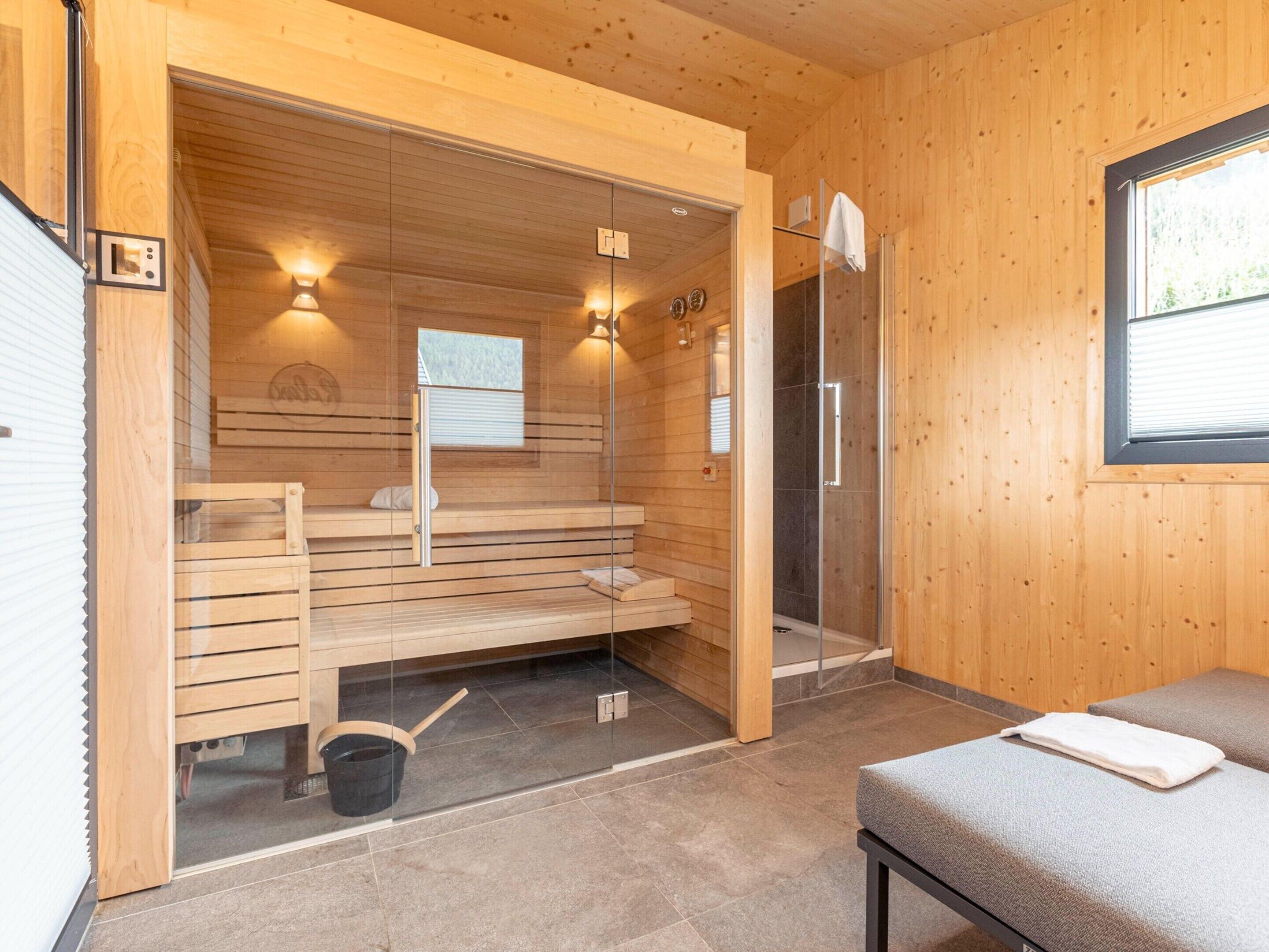 Una sauna con pareti in legno, una porta in vetro e una panca.