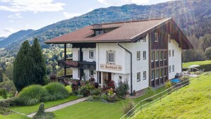A two-story building with a sign reading "Bodner." It features a red-tiled roof, multiple windows, and a balcony with potted plants. - Spacious Apartment in Afritz am See near Ski Area (Treffen)