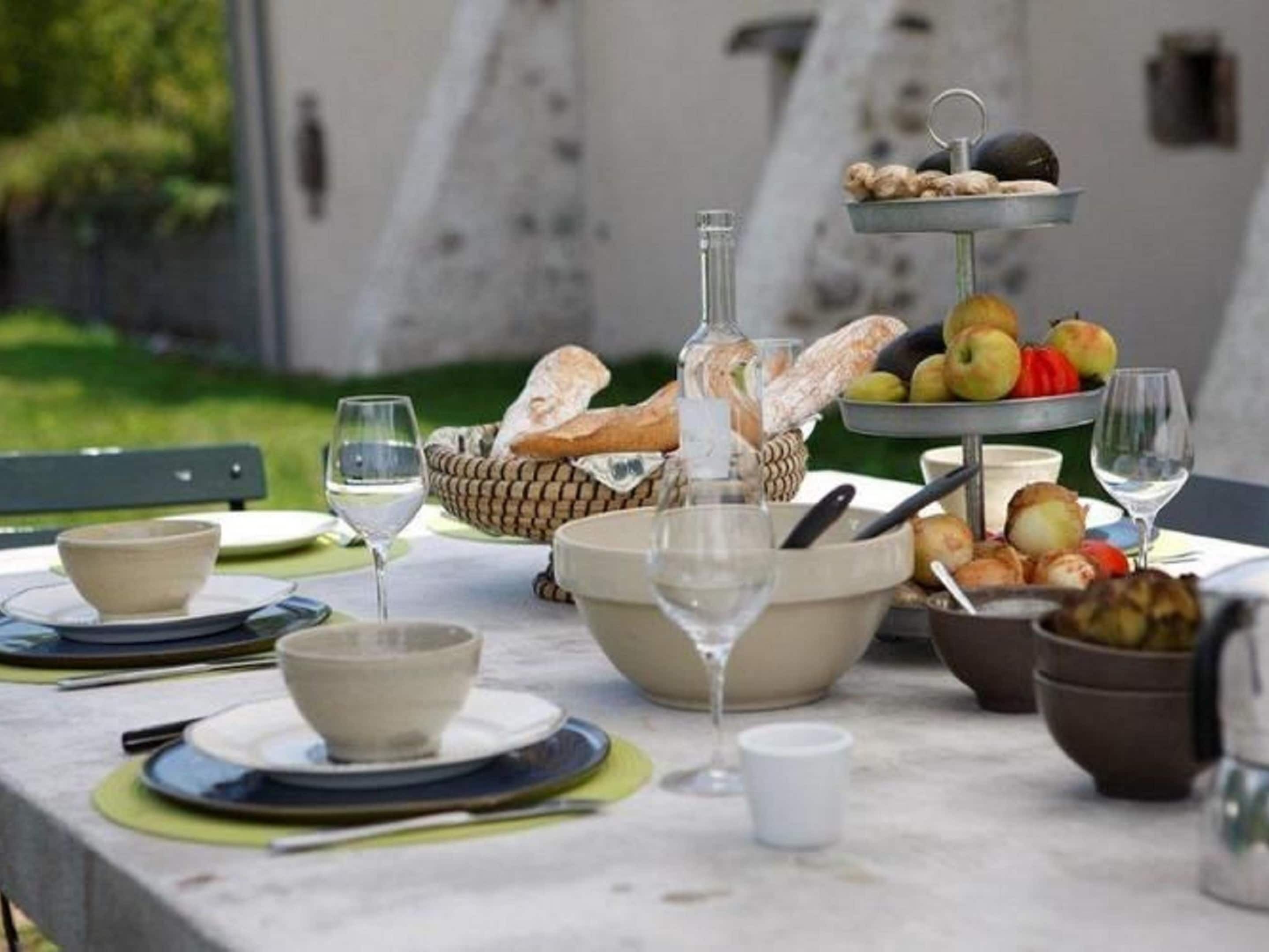 A table set for a meal with bread, fruits, and wine glasses.