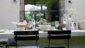 An outdoor dining area with a stone wall, a window with a view of greenery, and a variety of food and drink items on the table. - Luxurious Farmhouse in Braize (Braize)