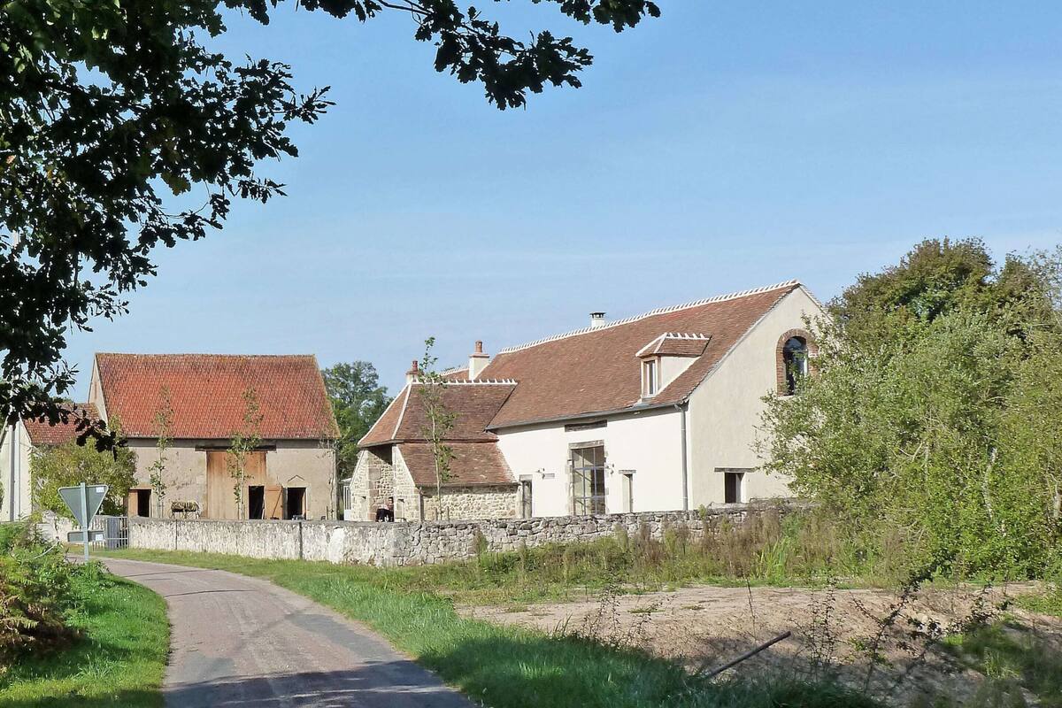 A rural road leading to a row of traditional stone houses with sloped roofs.