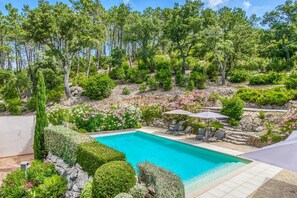A swimming pool surrounded by lush greenery and a stone wall. - Villa in Le Muy With Private Pool & Forest (Le Muy)