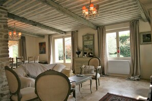 A room with a wooden ceiling, a chandelier, a sofa, a table, and a window with curtains. - Mas in Eygalieres With Heated Pool (Eygalieres)