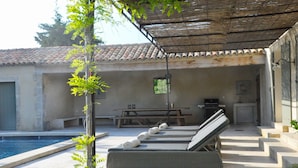 A poolside area with lounge chairs, a picnic table, and a covered patio. - Mas in Eygalieres With Heated Pool (Eygalieres)