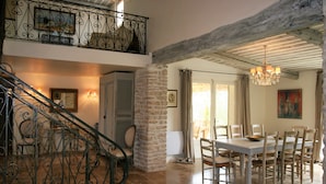 A dining area with a table and chairs, a staircase with ornate railings, and a chandelier. - Mas in Eygalieres With Heated Pool (Eygalieres)