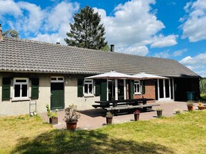 A building with a tiled roof, green shutters, and a covered patio with a bench. - Spacious Farmhouse near Forest in Stramproy (Stramproy)