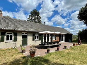 A building with a tiled roof, green shutters, and a covered patio area with benches. - Spacious Farmhouse near Forest in Stramproy (Stramproy)