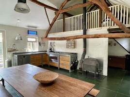 A kitchen with wooden cabinets, a large island, and a hanging pot rack.