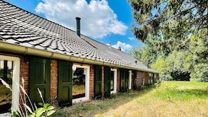A row of brick buildings with a tiled roof, green doors, and a grassy area in front. - Spacious Farmhouse near Forest in Stramproy (Stramproy)
