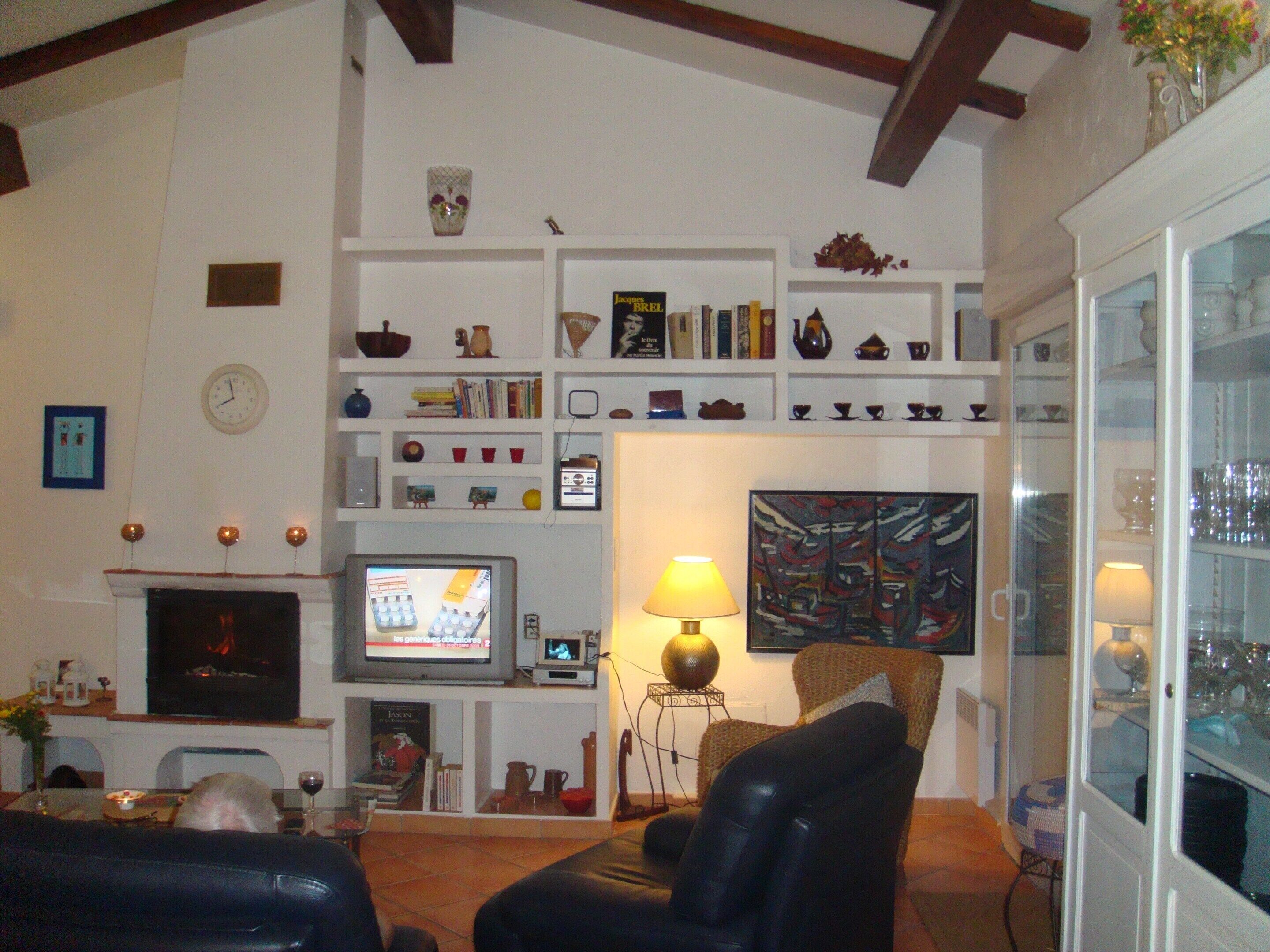 Ein Wohnzimmer mit Kamin, Fernseher, Bücherregalen und einem Gemälde.