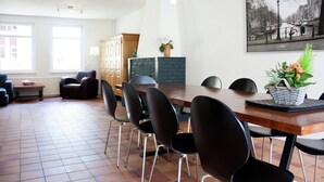 Un'area pranzo con un tavolo in legno, sedie nere, un vaso con fiori e un quadro appeso al muro.