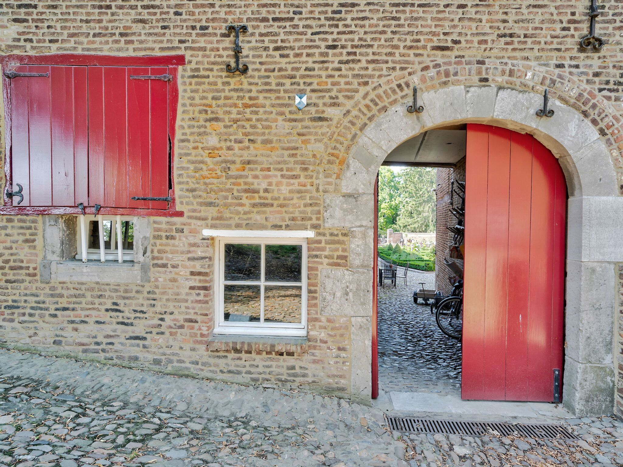 A brick building with a red door and a small window.