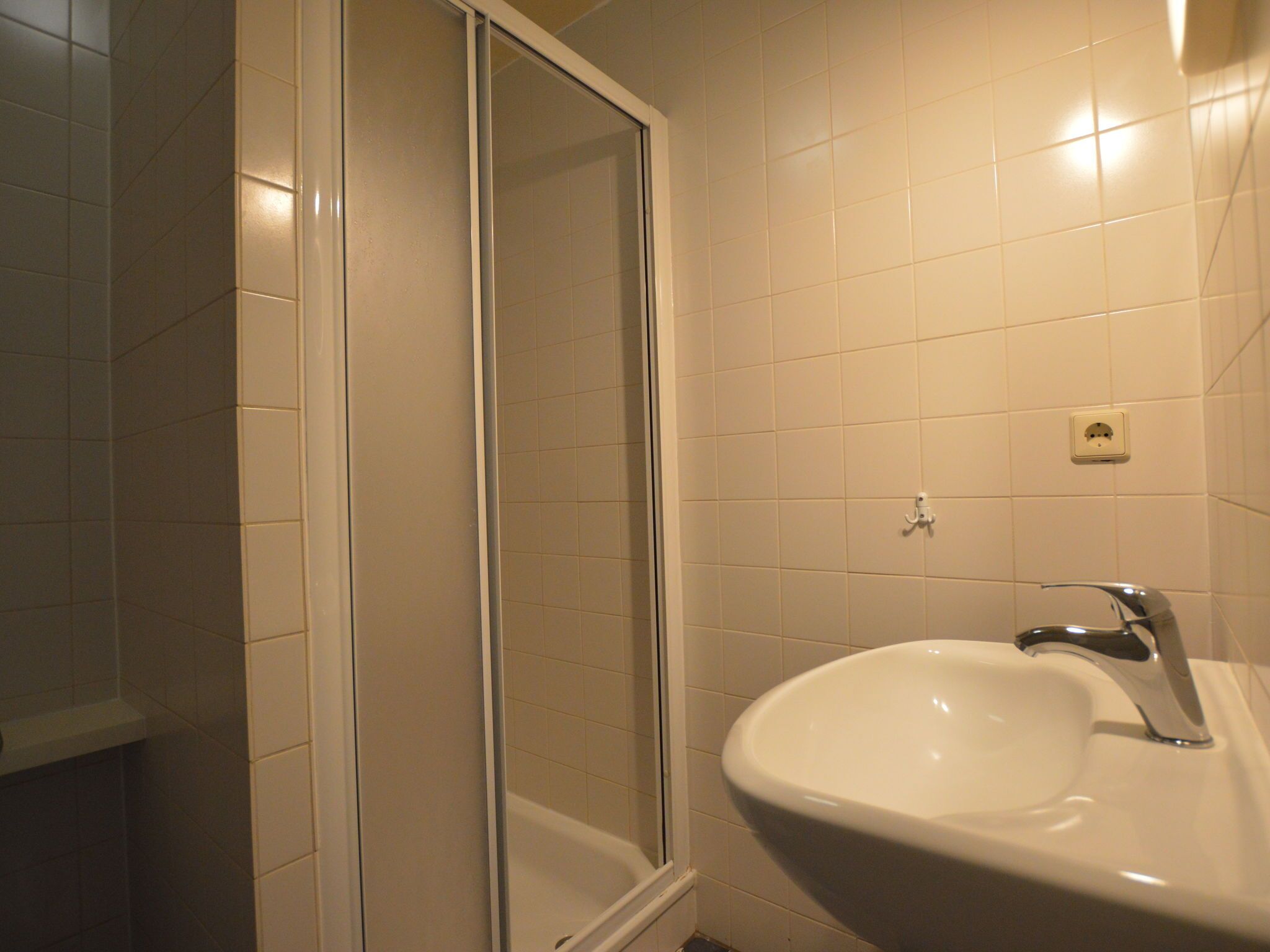 Un bagno con un lavandino bianco, uno specchio e una doccia con porta in vetro.