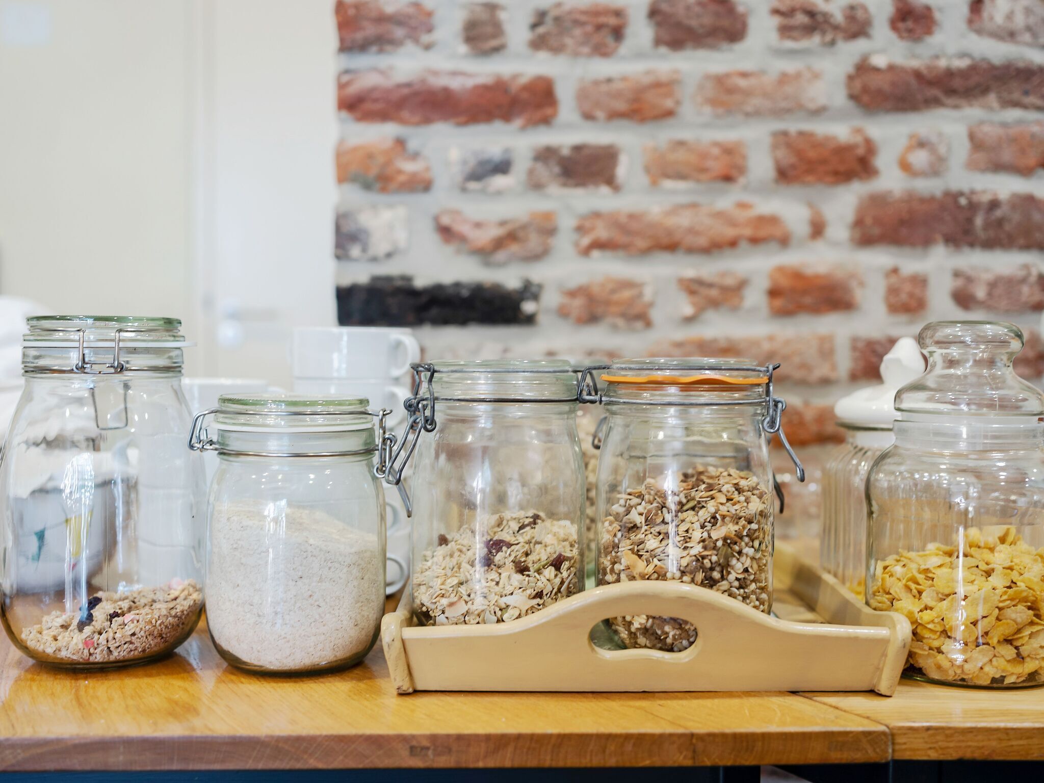 A wooden table with several glass jars containing various grains and seeds.