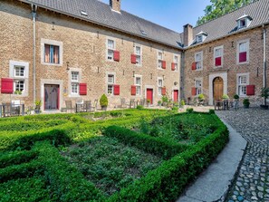 A courtyard with a brick building, red shutters, and outdoor seating. - Apartments "meschermolen" Near Maastricht (Eijsden)